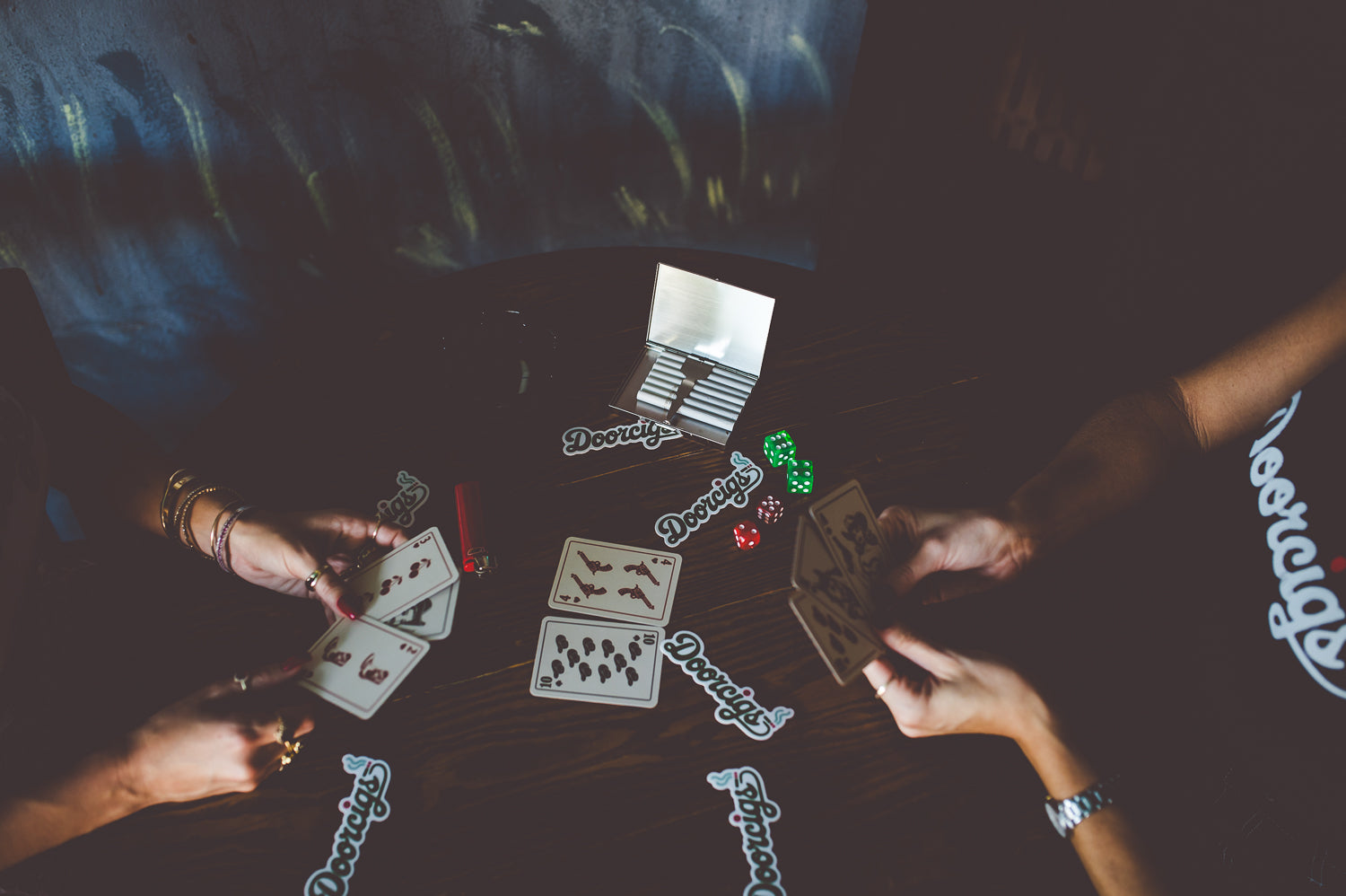 Lifestyle photo of girls playing cards with beers — Doorcigs luxury streetwear brand vibe.